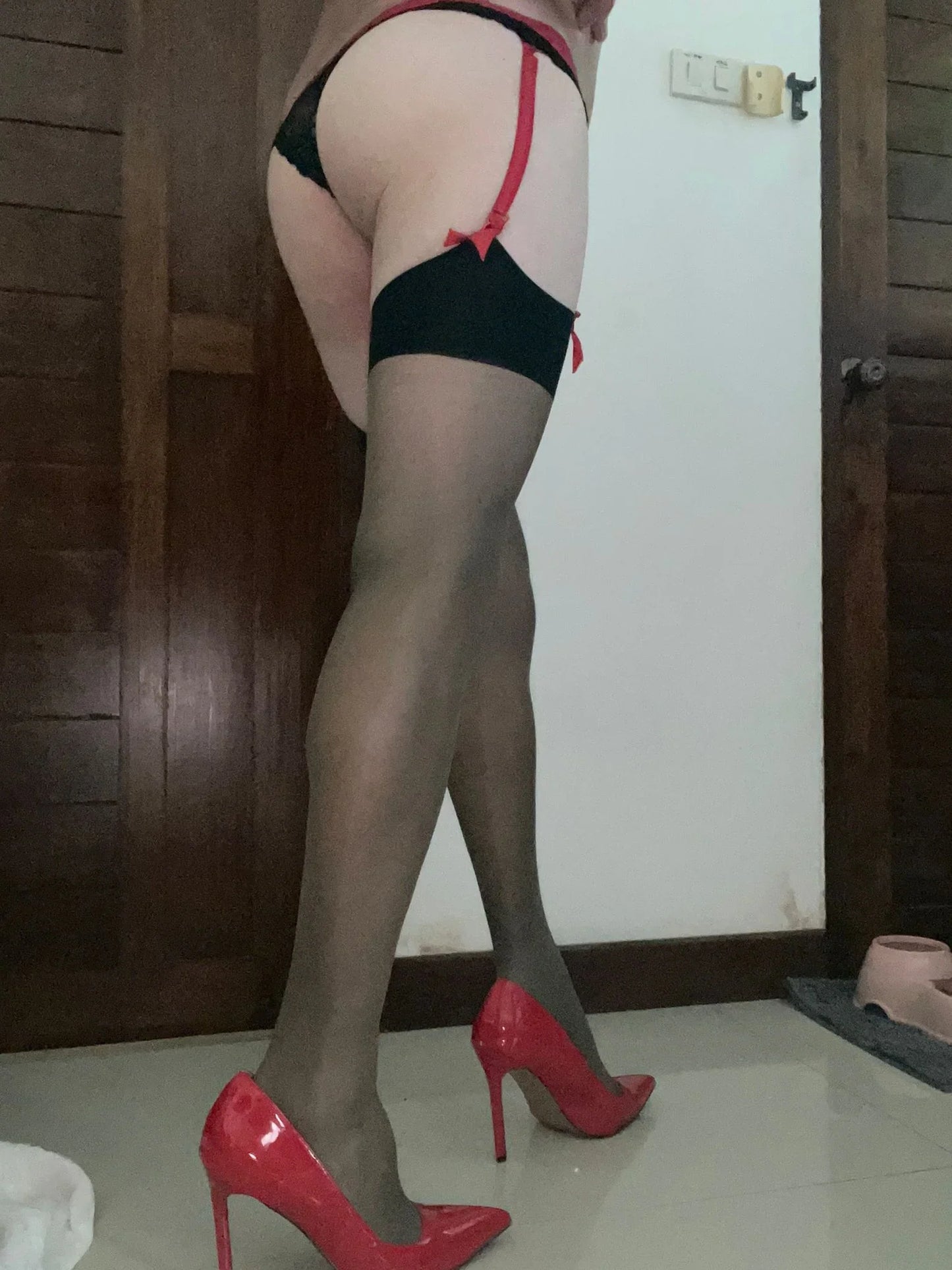 a man wearing black stockings with a red suspender belt