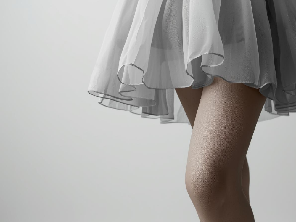 Close-up of a person wearing a white skirt with a plain background